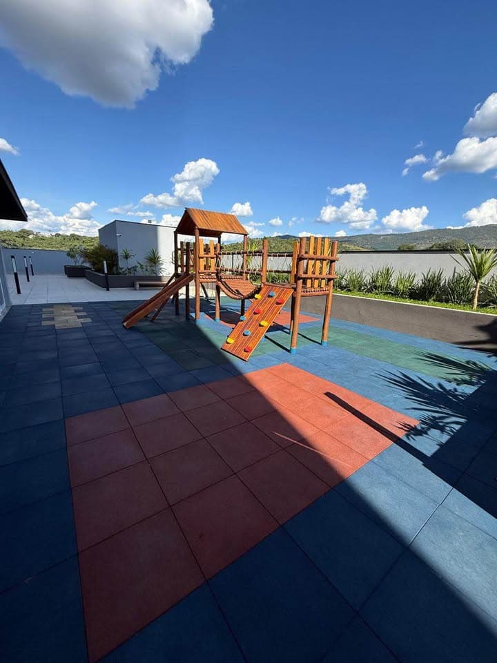 Playground infantil com estrutura de madeira sobre piso emborrachado colorido.