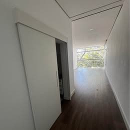 Salão comercial com piso amadeirado e porta de correr branca.