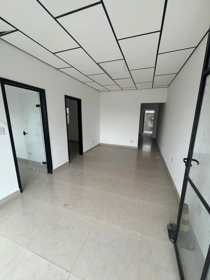 Ambiente interno comercial com portas pretas, piso em cerâmica clara e teto modulado