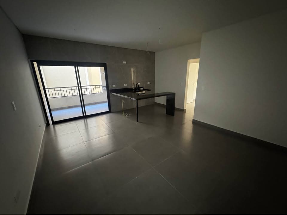 Sala ampla com piso em porcelanato cinza, parede de destaque texturizada e acesso à varanda